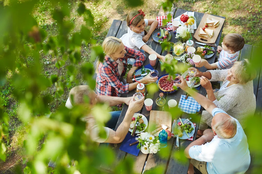 Familie und Freunde stoßen bei einer gemeinsamen Mahlzeit im Garten an