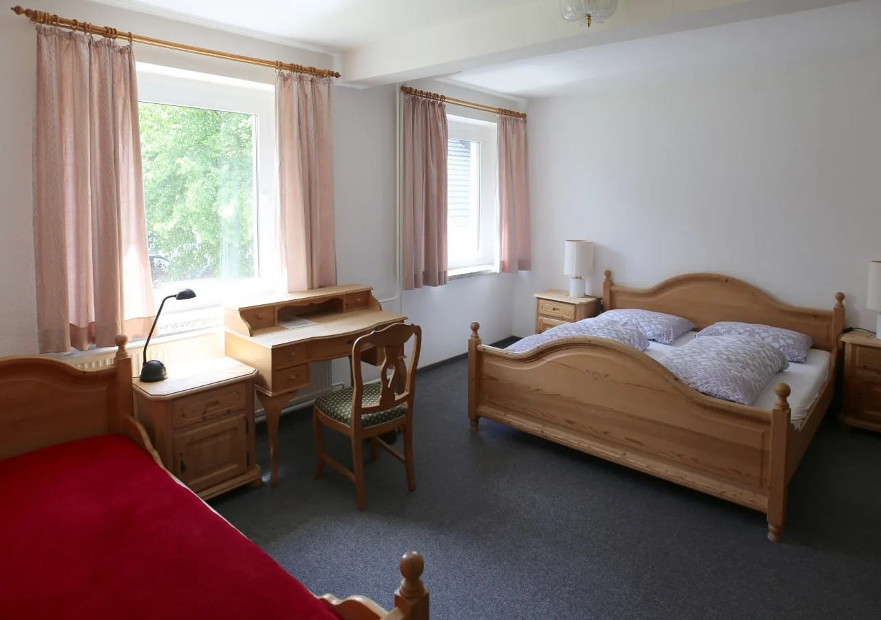 Helles Mehrbettzimmer mit Holzmöbeln und Schreibtisch