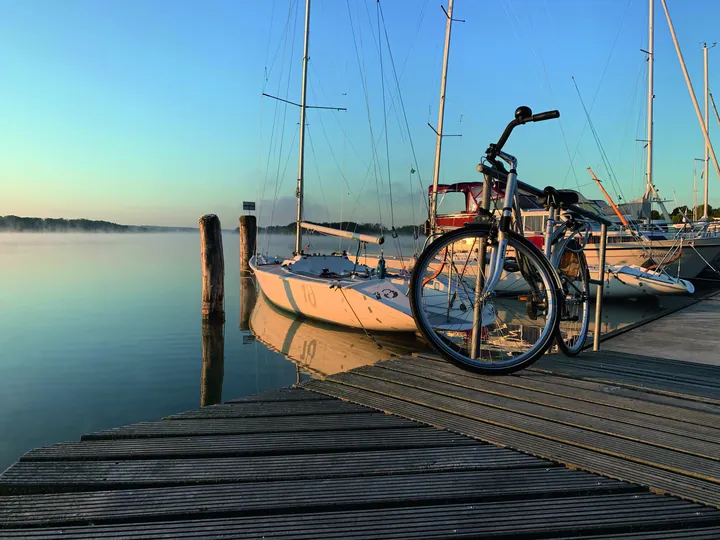 Fahrrad und Segelboote im morgendlichen Hafen